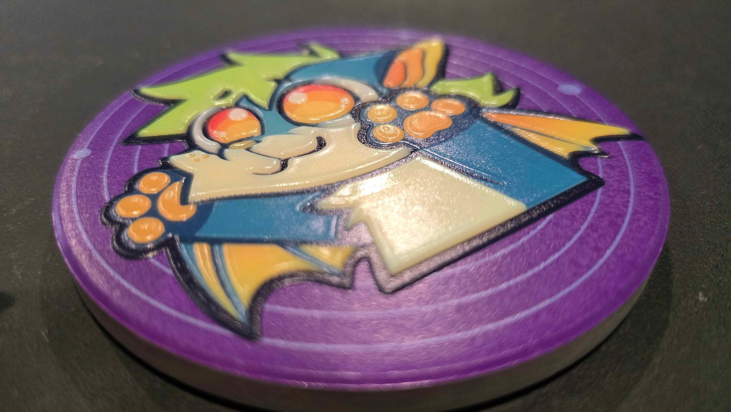 A circular purple game token or coin featuring a cartoon bat character with orange eyes, yellow wings, and a blue body, photographed on a dark surface.